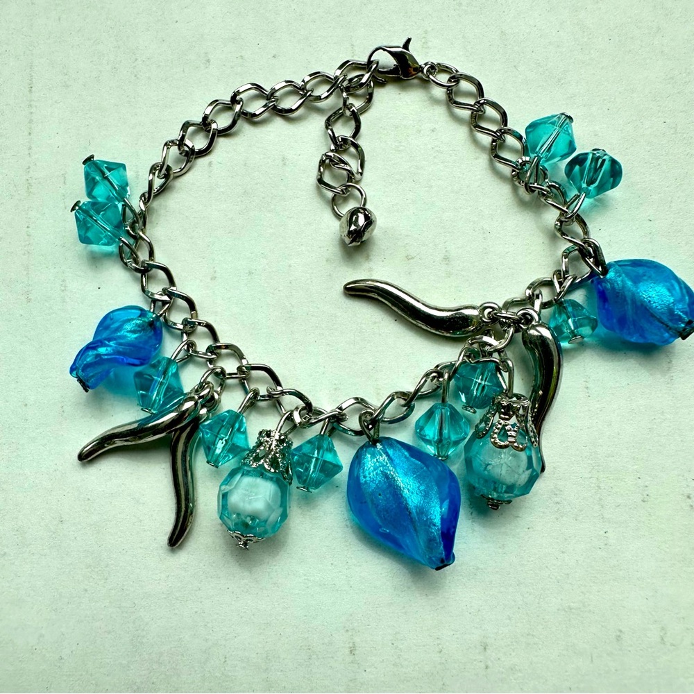 Silver colored metal bracelet with charms and glass blue beads